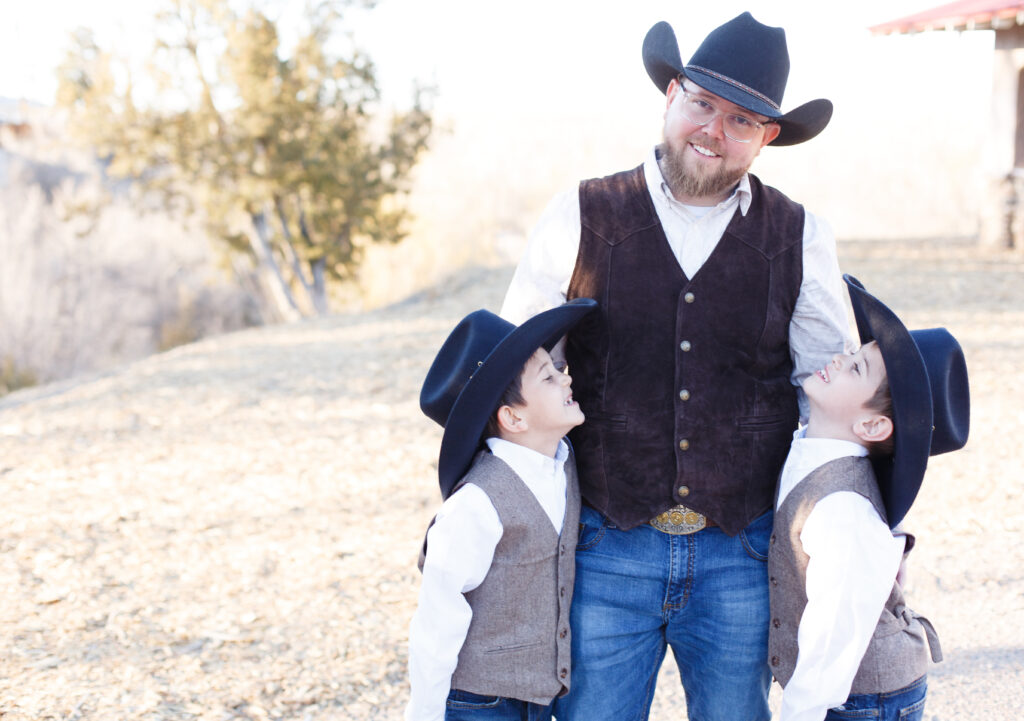 Dad smiles at the camera while his two sons smile up at him in City Park