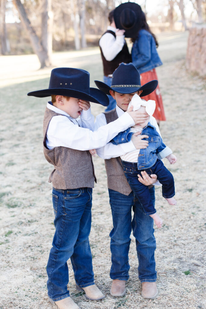 Three kids stand in the foreground while mom and dad kiss in the background in Pueblo CO