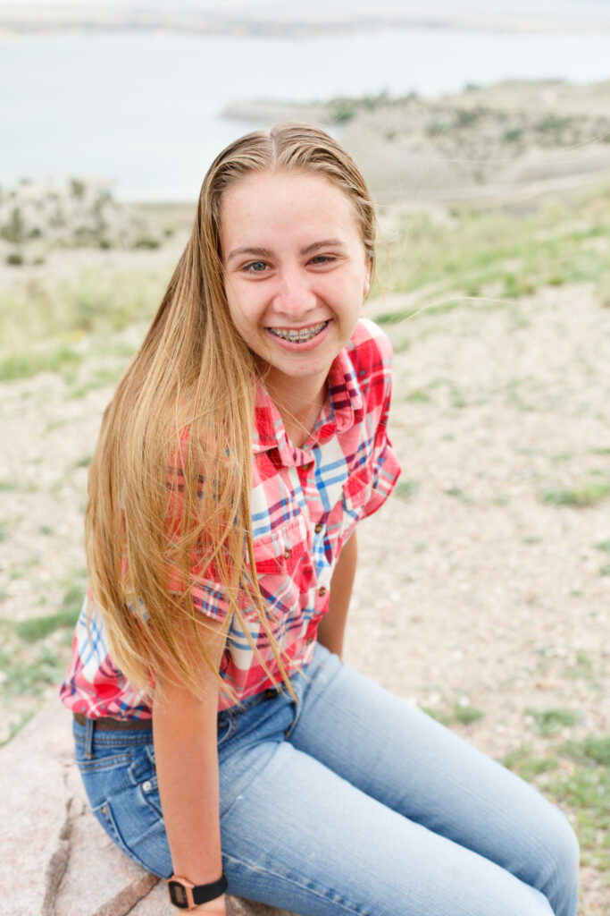 girl sits on rock smiling up to camera