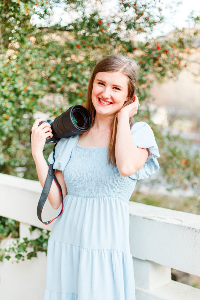 Girl rests her camera on shoulder and smiles