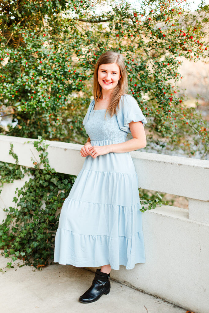 Girl leans against short wall and smiles