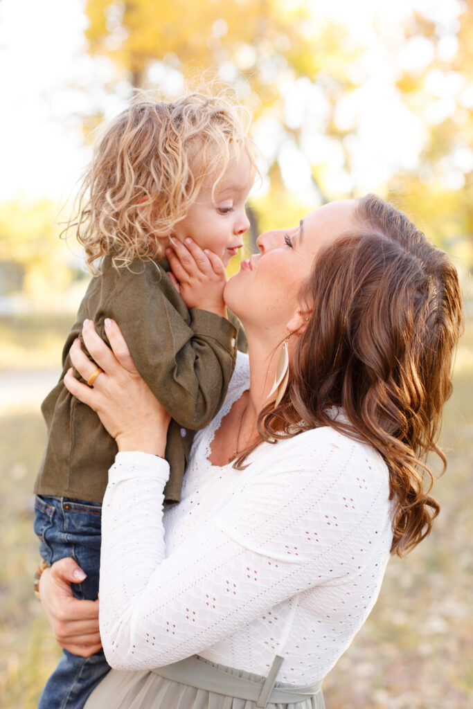 Mom holds toddler and they smile at each other in fall family session