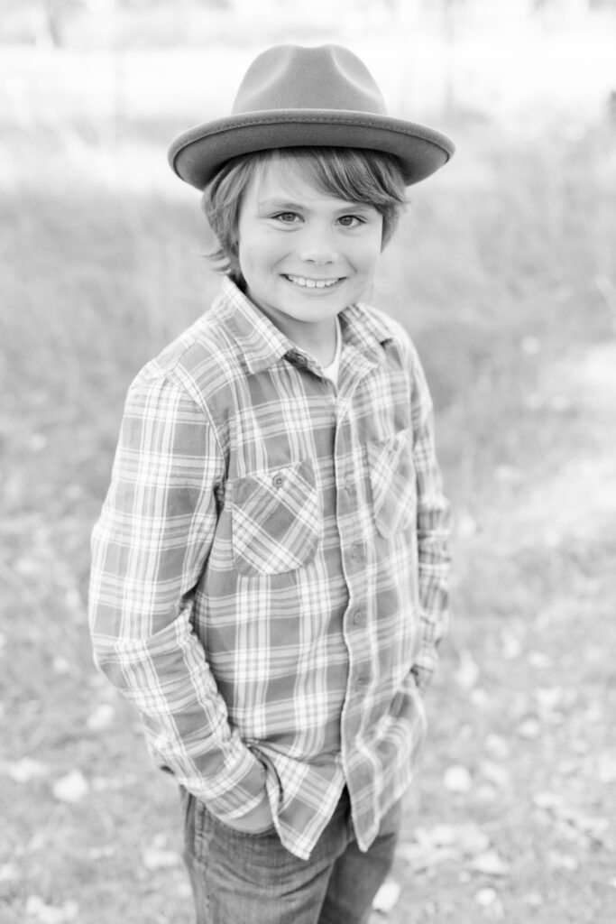 Boy wears hat and smiles at camera in City Park CO