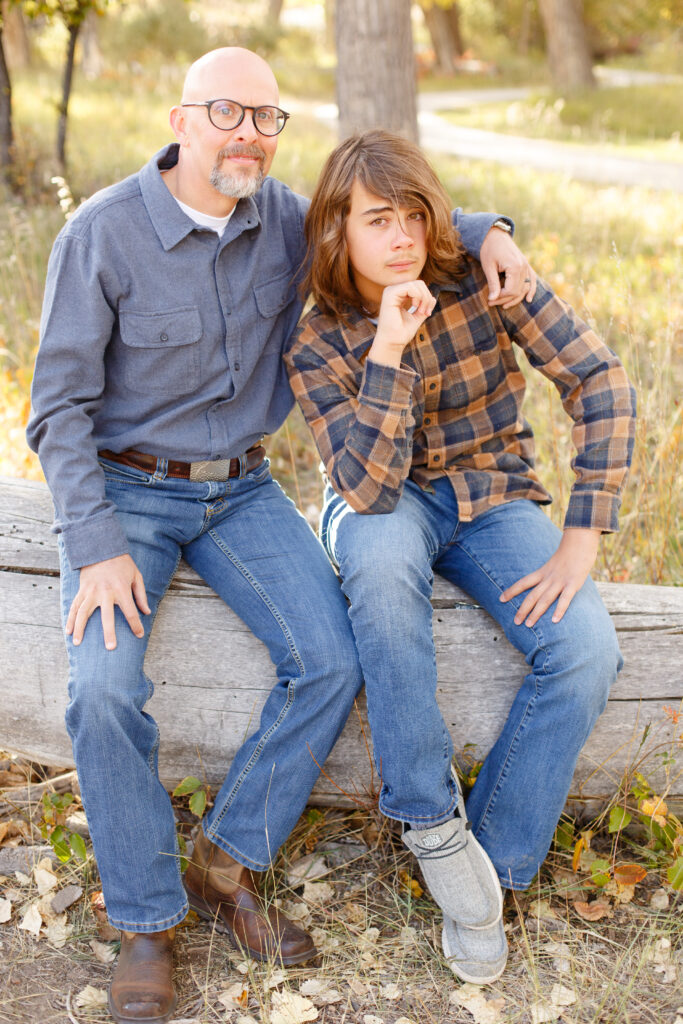 Dad and son sit together and son rests chin on hand in City Park