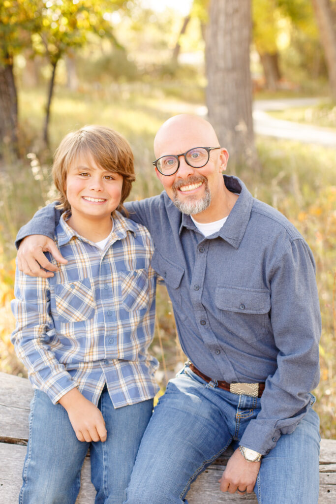 Dad and son sit on fallen log in City Park