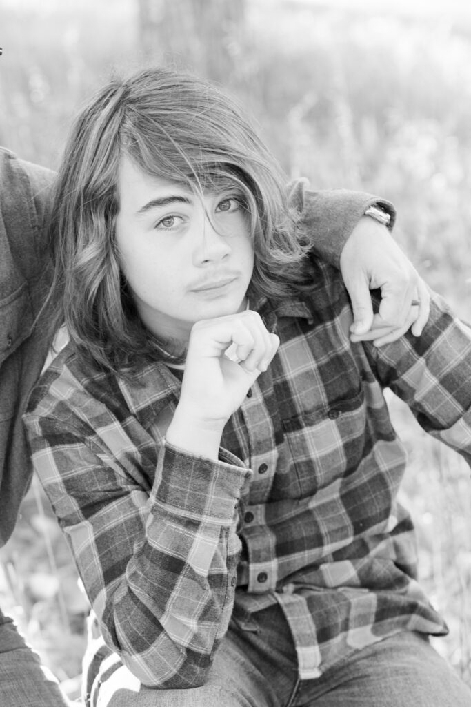 Boy rest his chin on hand while sitting on log in City Park