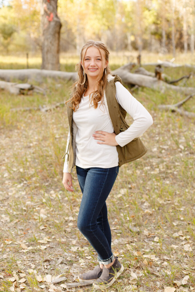 Daughter rests hand on hip and smiles in City Park CO