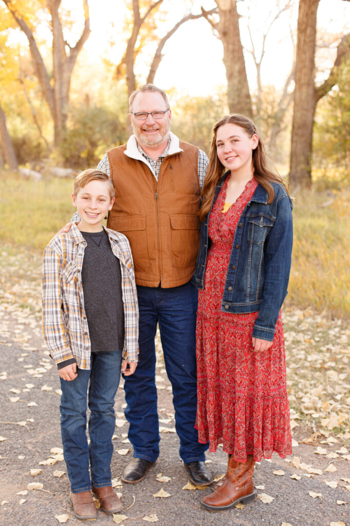 Dad and kids stand together in City Park, Pueblo CO at fall family mini session