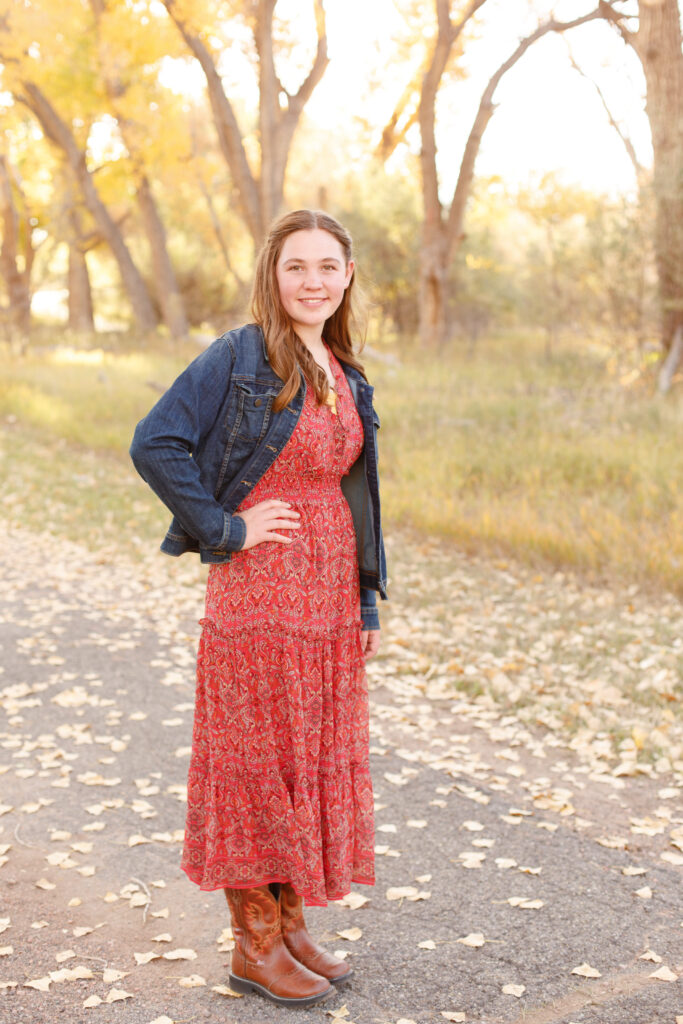 Girl rests hand on hip and smiles at fall family mini session in City Park, Pueblo CO