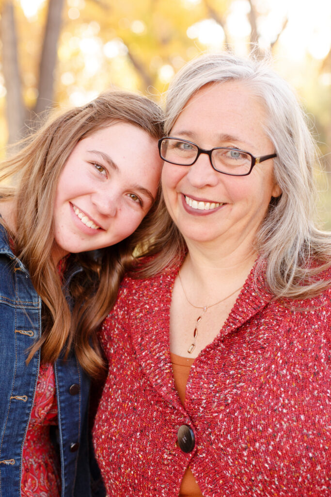 Daughter rests head on mom's shoulder at fall family mini session in Pueblo CO