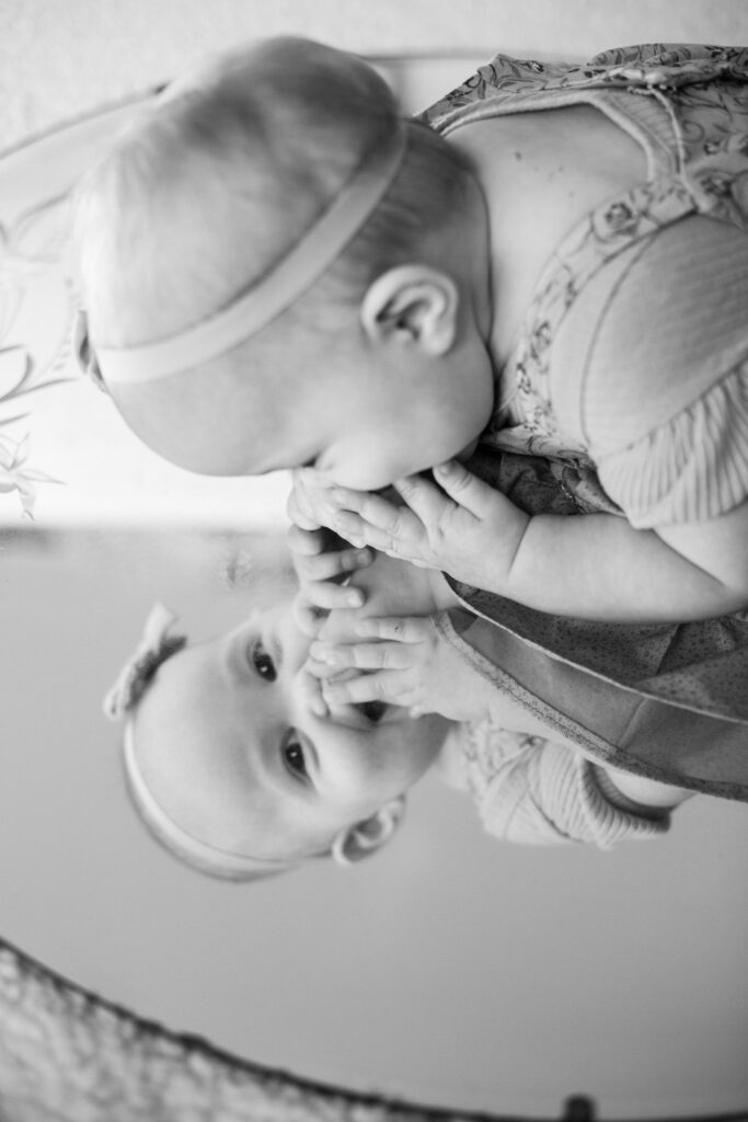 Baby laughs at herself in mirror at milestone mirror session in Pueblo West CO