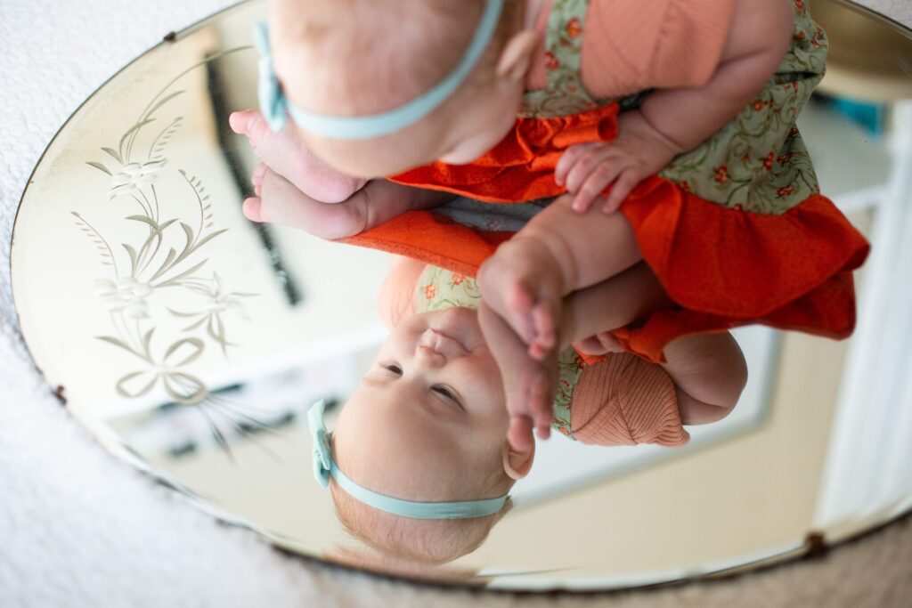 Baby looks into mirror at milestone mirror session