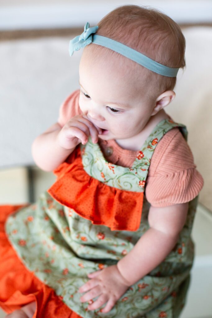 Baby sits on mirror with finger in mouth