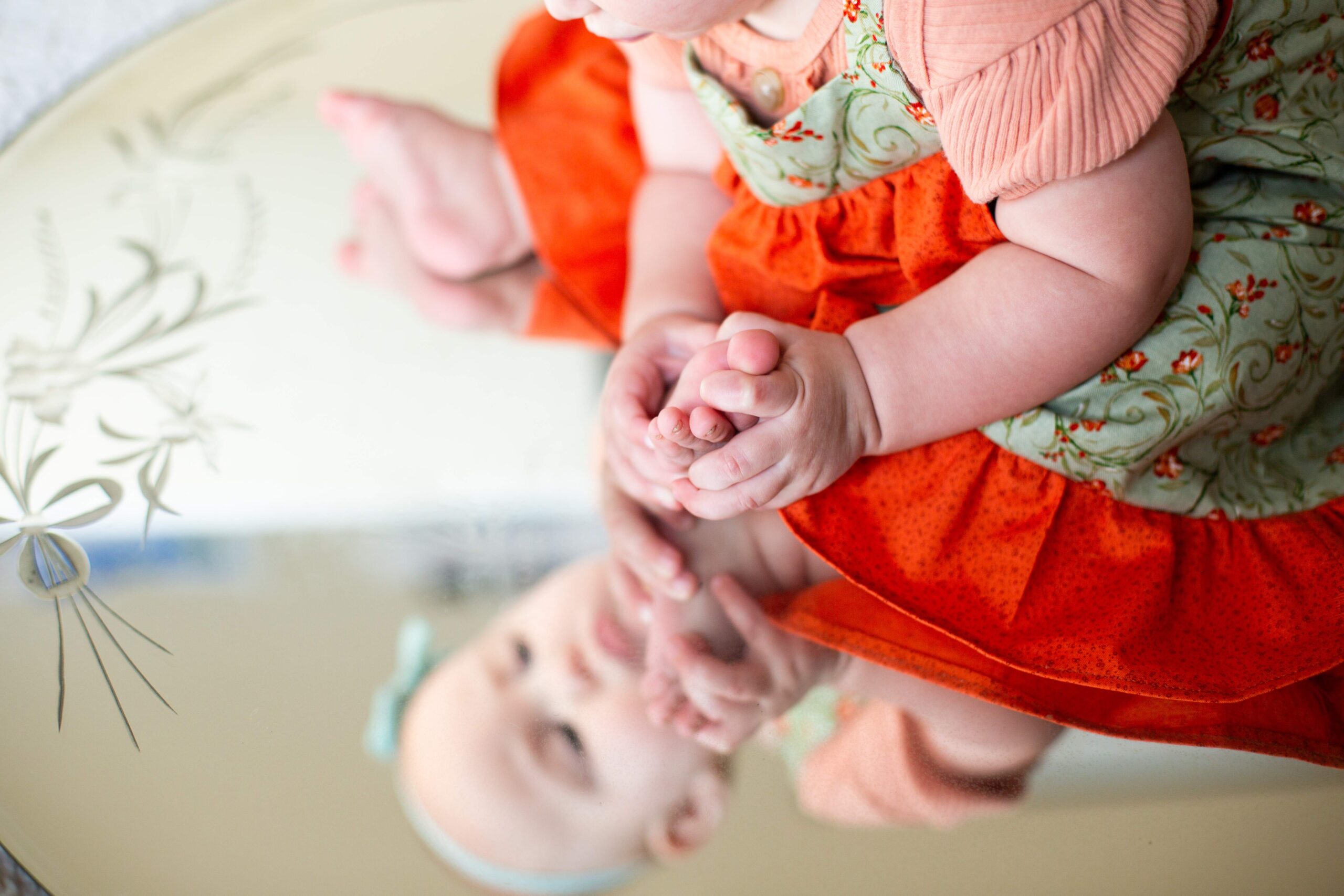 Baby holds her foot in milestone mirror session in Pueblo West CO