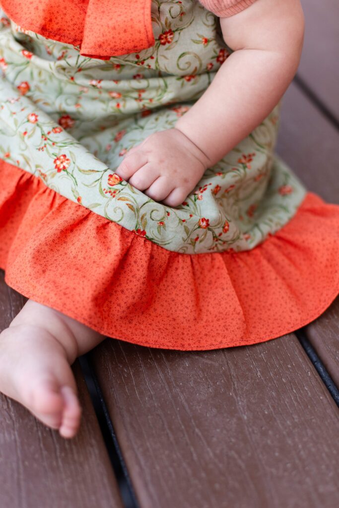 Baby rests hand on dress at milestone mirror session