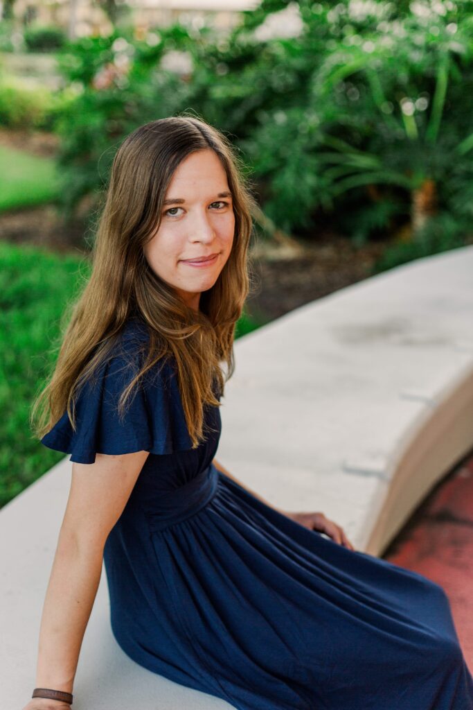 Girl sits on a low wall during her destination session in Orlando Florida.