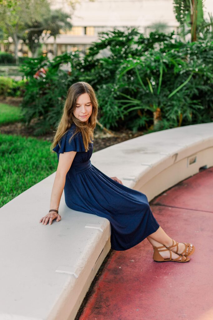 Girl sits on a low and looks down at beautiful destination session in Orlando Florida.
