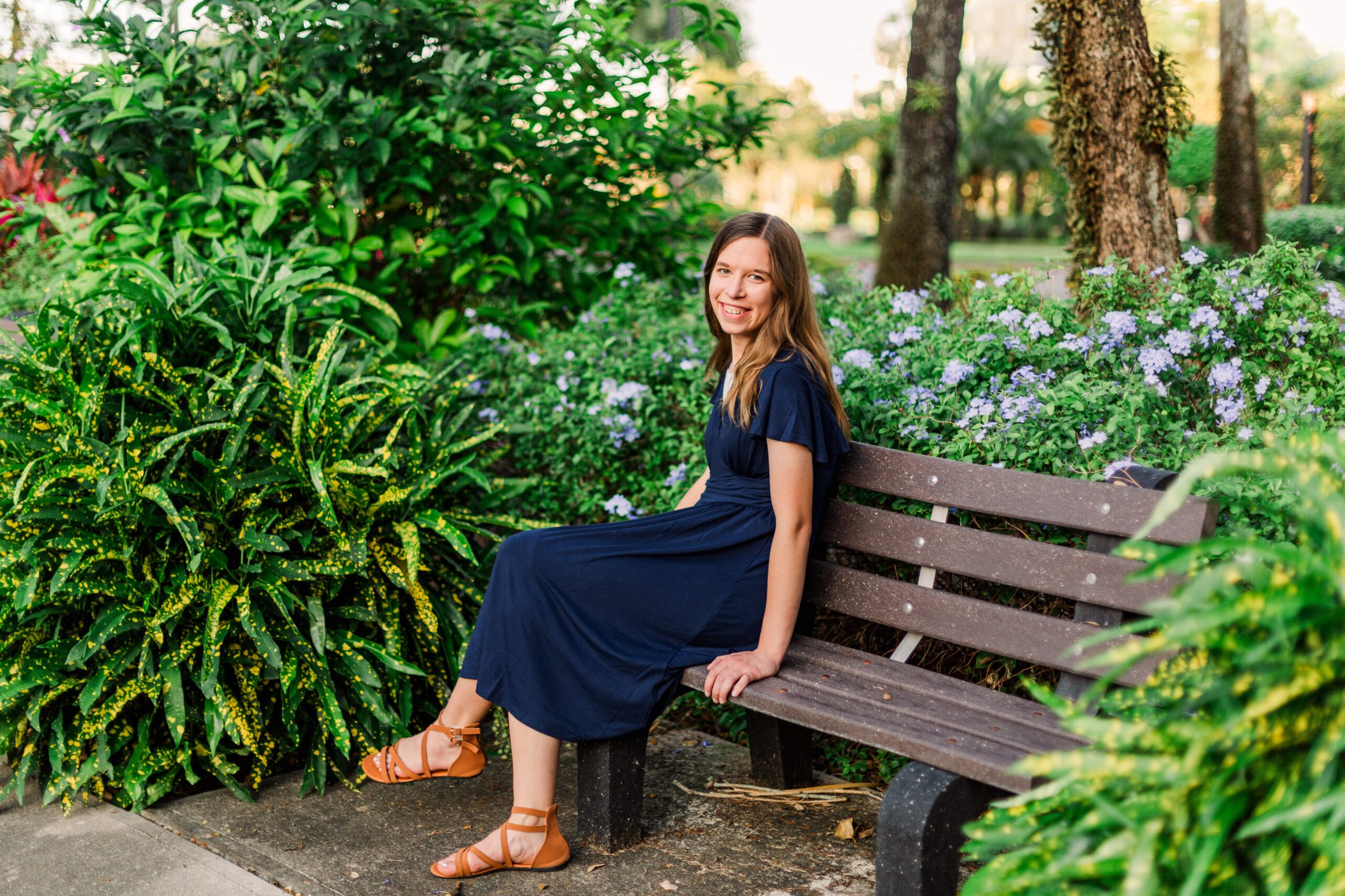 Girl sits on bench and smiles at beautiful destination session in Florida.