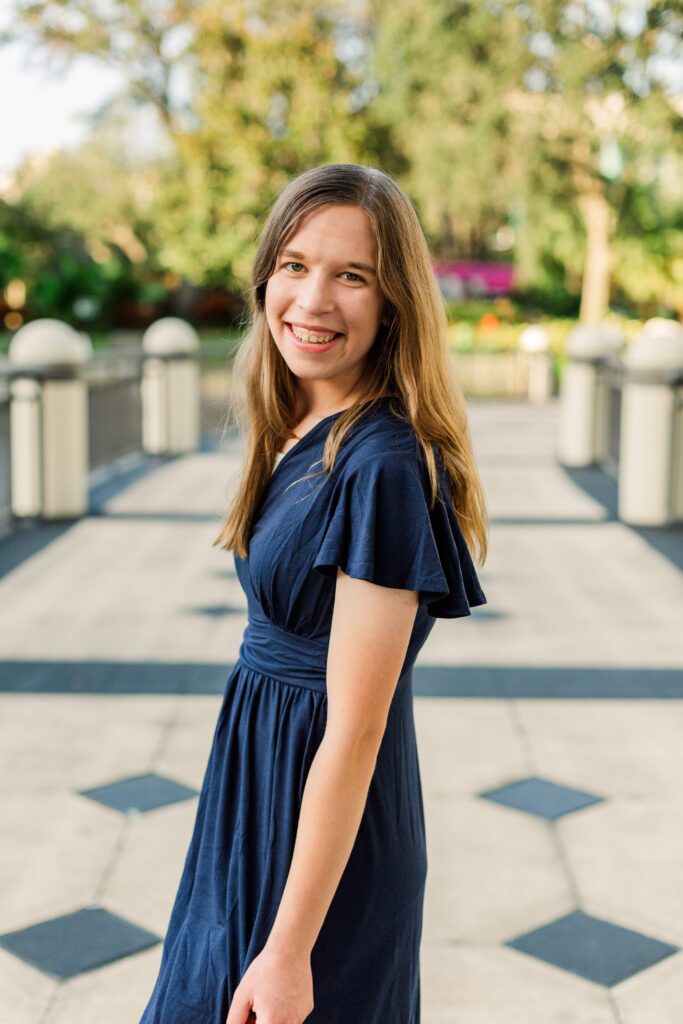 Girl stands on bridge and smiles at beautiful destination session in Florida.