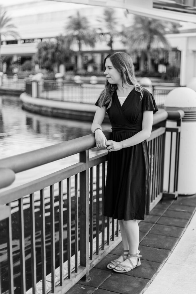 Girl rests her elbow on the rail and looks over the water at beautiful destination session in Orlando Florida.