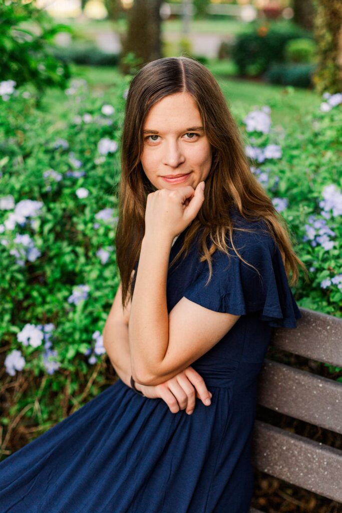 Girl rests her chin on her hand and smiles at the camera.