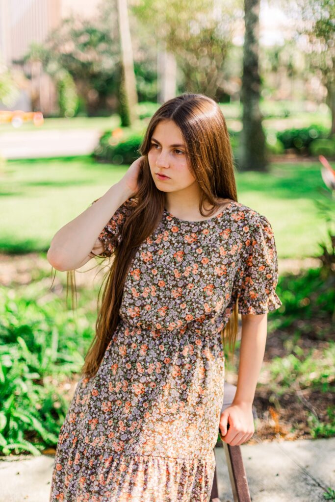 Girl tucks hair behind her ear during scenic portrait session.