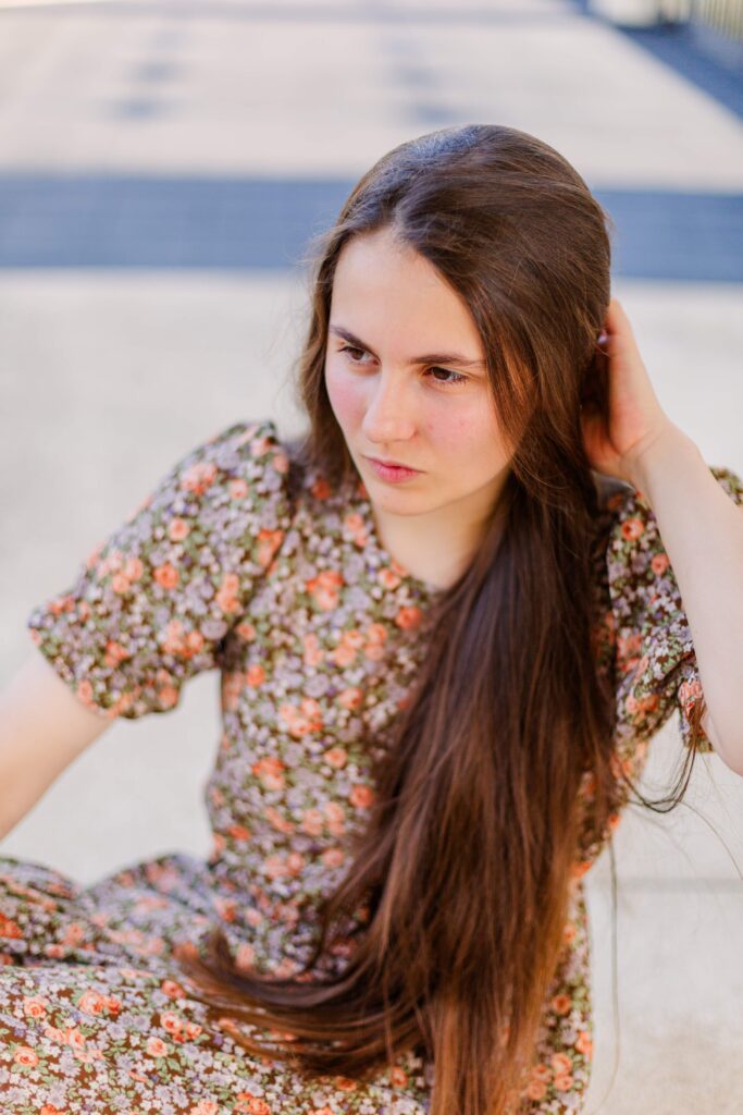 Girl sits on the ground looking contemplative.