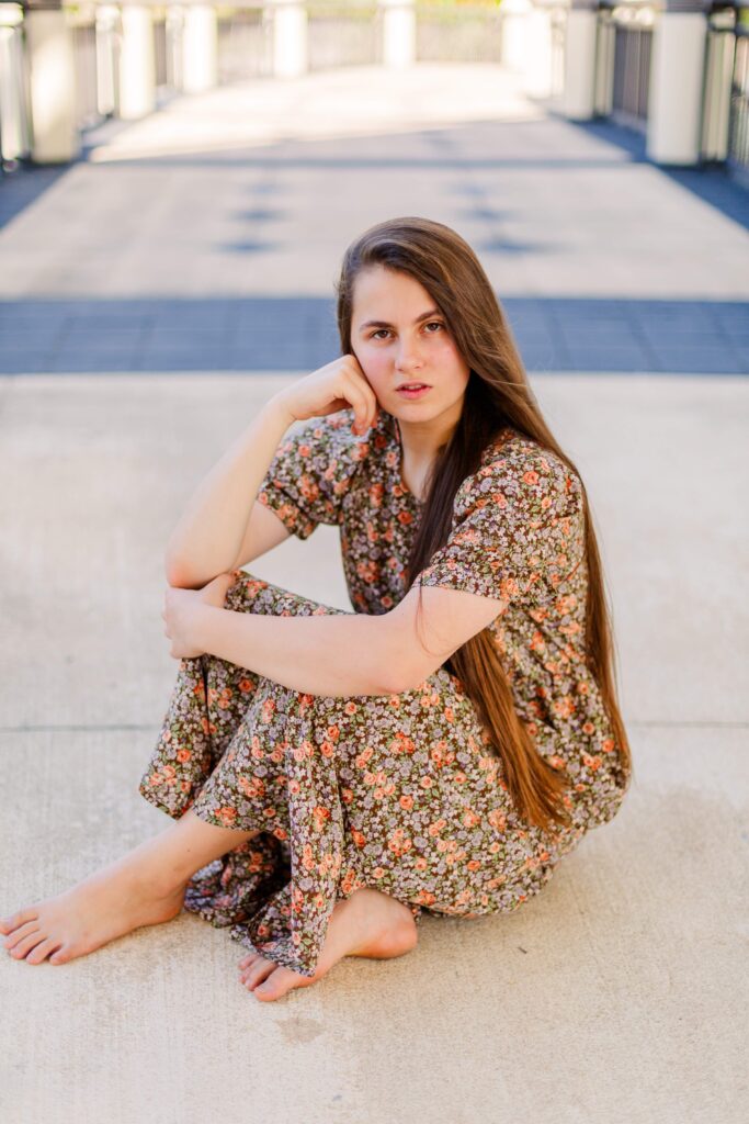 Girl sits with feet crossed during scenic portrait session in Orlando Florida.