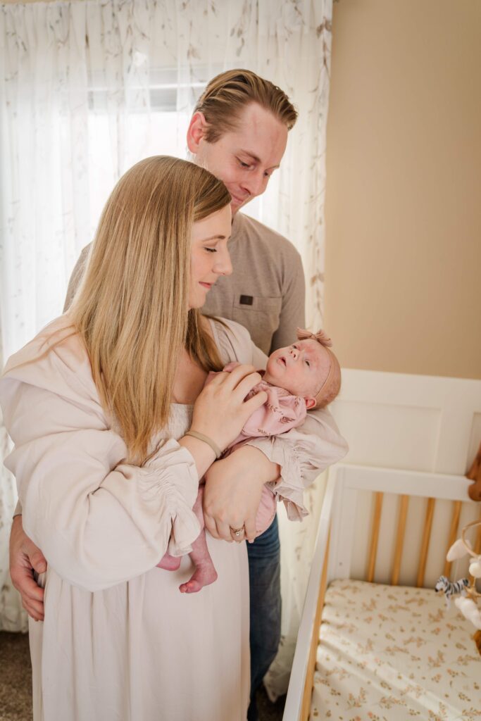 Mom and Dad stand in front of the crib during in home lifestyle newborn session