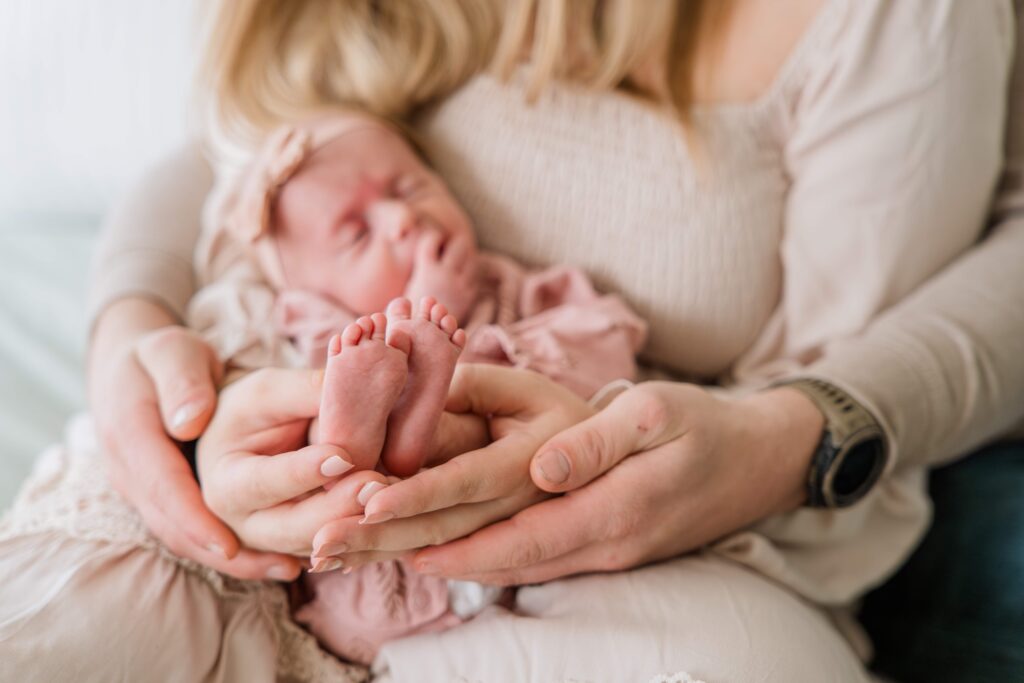 Baby's parents hold her feet during in home newborn session.