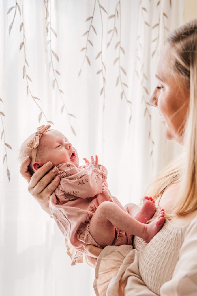 Mom holds baby out in front of her and smiles.