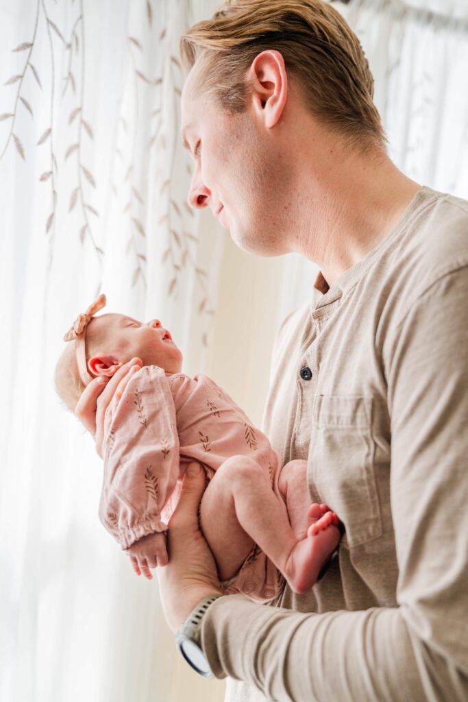 Dad holds newborn in front of him.