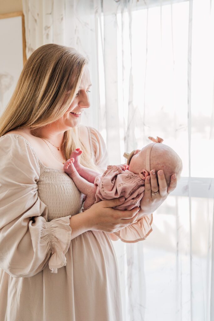 Mom holds baby by the window.