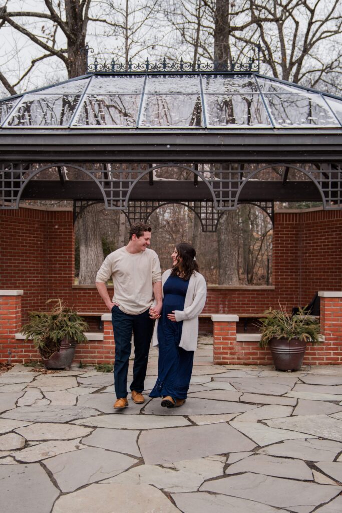 Couple walks away from the arbor and laugh together.