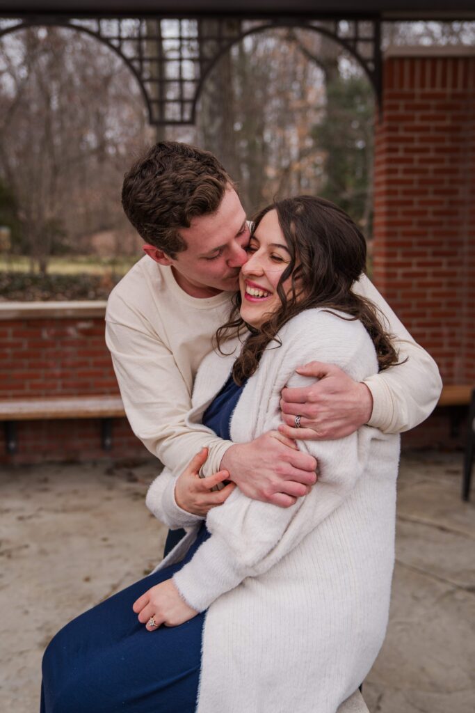 Husband and wife laugh under an arbor.