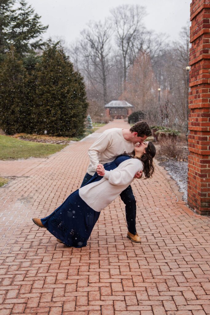 Husband dips wife on a snowy path.