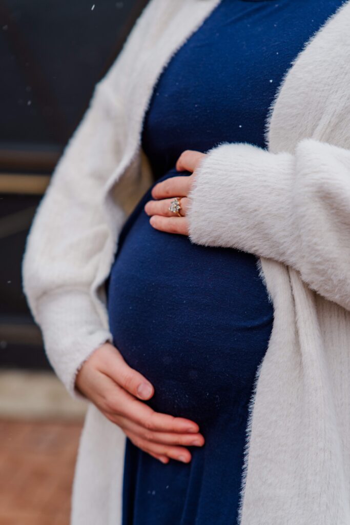 Mom's hands cradle her baby bump.