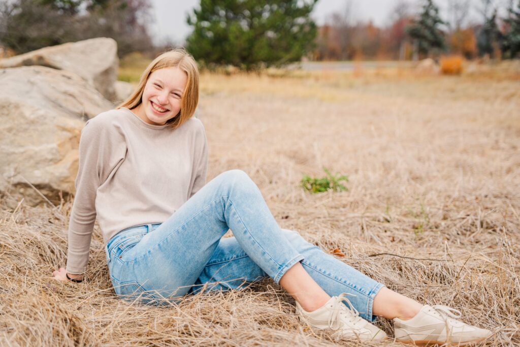 Girl smiles at a camera while sitting on the ground