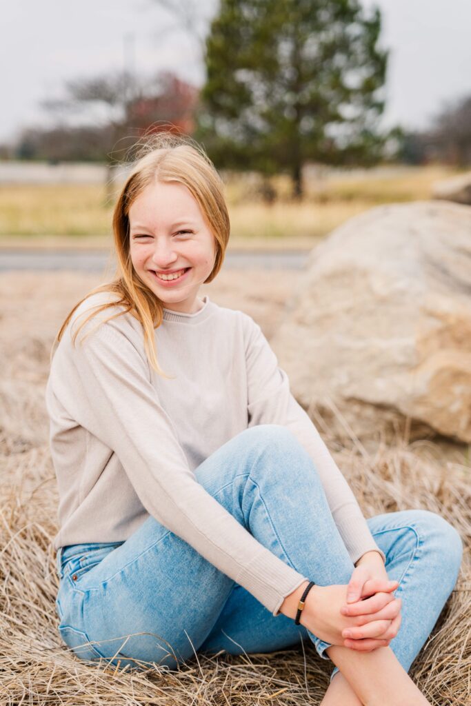 Girl hugs her knee and smiles.