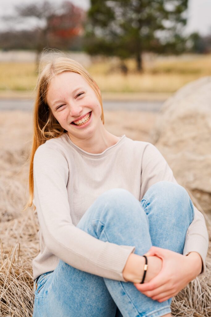 Girl has her hands wrapped around her knees.