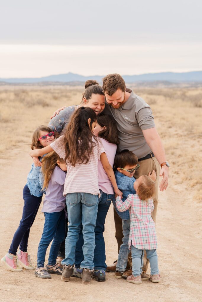 Kids hug parents. Youngest looks up.