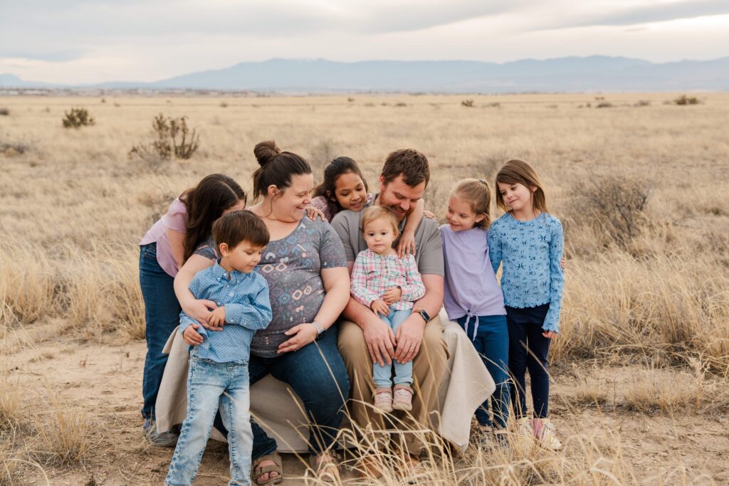 Family smiles at the toddler sitting on Dad's lap.