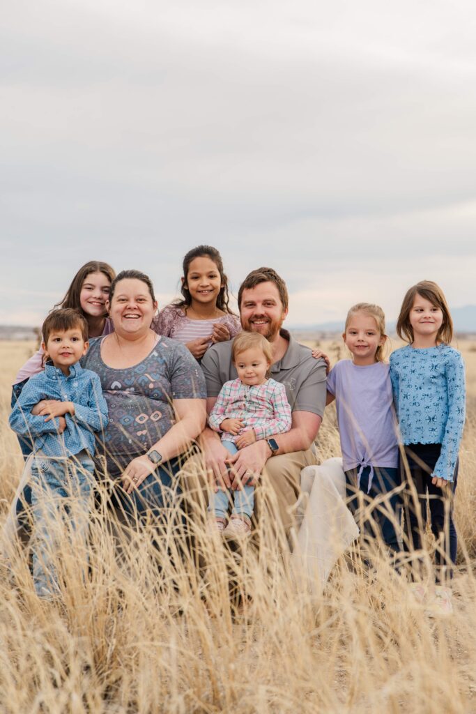Family smiles at the camera while sitting.