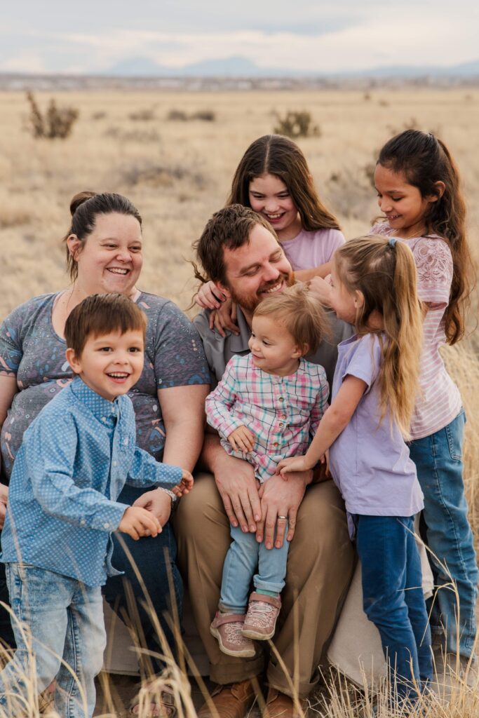Girls rest their arms on Dad's shoulder.