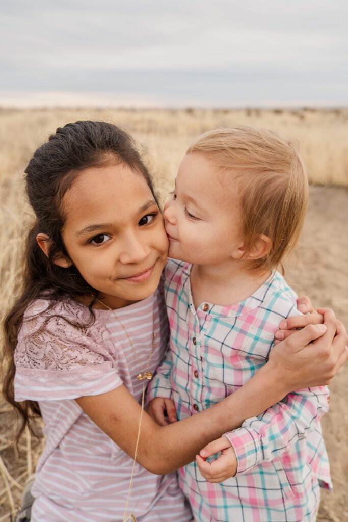 Toddler kisses sister.