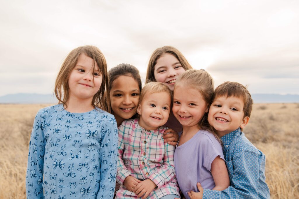 All the kids stand close and smile.