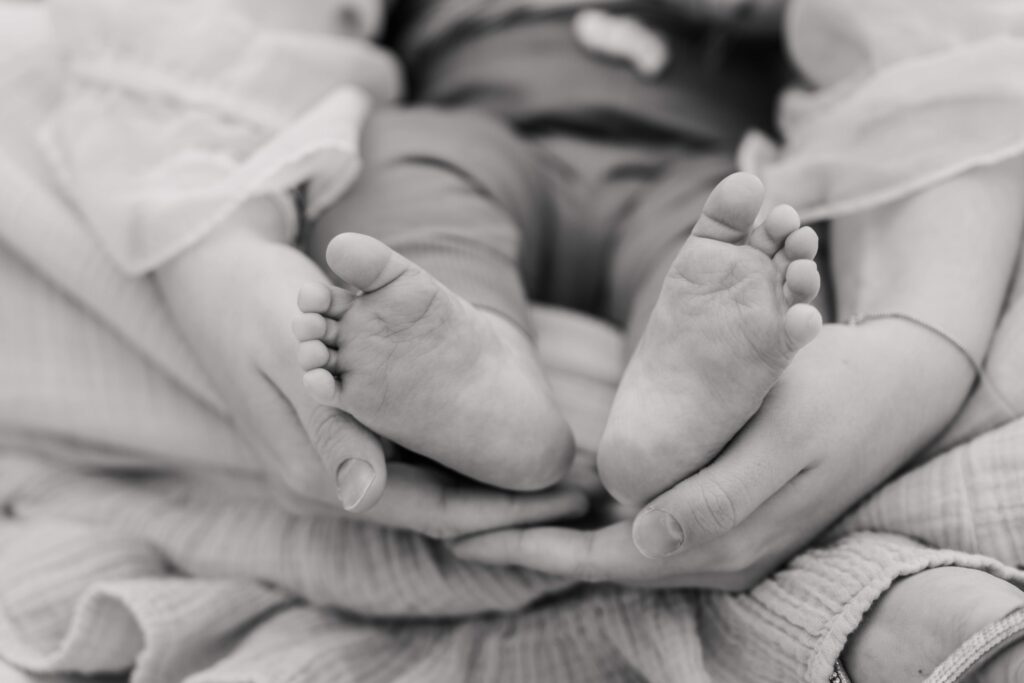 Black and white image of mom cupping baby's feet at a mommy & me session in Sandusky Ohio.