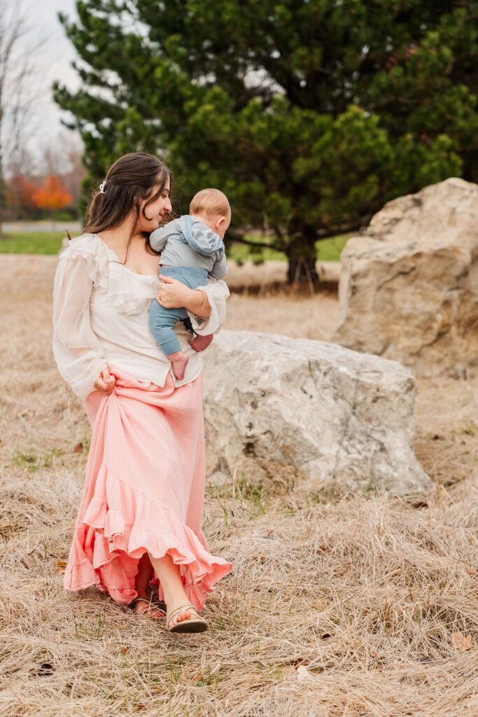 Mama lifts the edge of her hem while waling with baby.