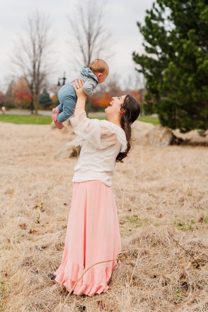 Mom and baby laugh as Mom tosses the baby in the air.