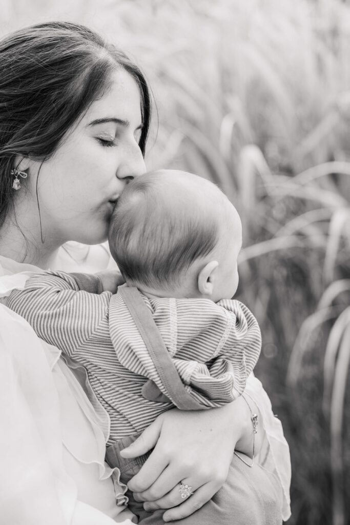 Black and white of mom kissing baby's head.